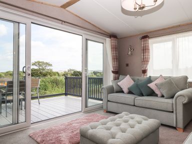 A living room with a sofa and sliding doors at Maple Lodge in Teigngrace near Kingsteignton