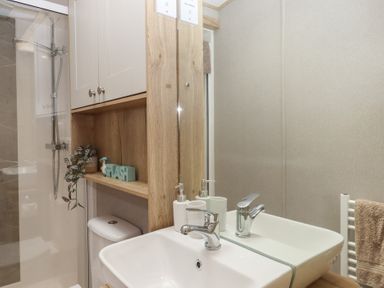 A bathroom with shower, sink, and white cabinetry at Maple Lodge Teigngrace near Kingsteignton