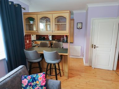A kitchen with bar stools and cabinets at Kathleens Cosy Apartment in Galway