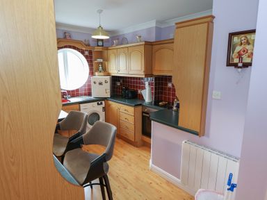 A kitchen with cabinets and appliances at Kathleens Cosy Apartment in Galway