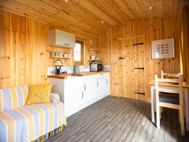 A kitchen with wooden walls and a table at Head For the Hills Glamping - Skylark Shepherd's Hut