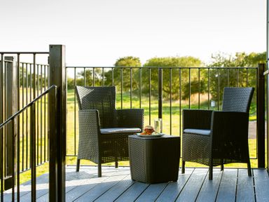 A patio with two chairs and a table holding a drink and food at Head For the Hills Glamping - Skylark Shepherd's Hut