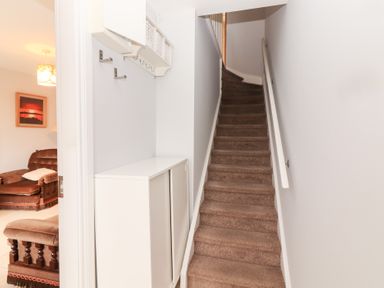 A hallway with a staircase and storage cabinet at 1 Windermere in Kinvarra