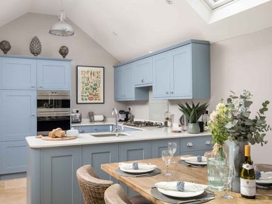 A kitchen with light blue cabinets and dining area at Lavender Cottage (Stow-on-the-Wold) Cheltenham
