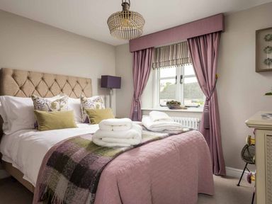 A bedroom with a bed, bedside lamp, and curtains at Lavender Cottage (Stow-on-the-Wold) Cheltenham