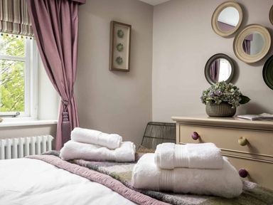 A bedroom with towels on the bed and a dressing table in Lavender Cottage (Stow-on-the-Wold) Cheltenham
