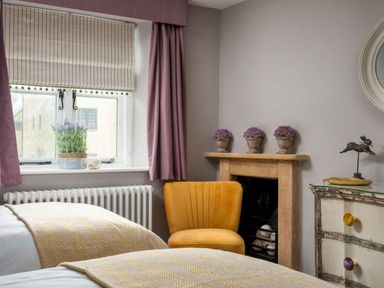A bedroom with twin beds and a yellow chair at Lavender Cottage (Stow-on-the-Wold) Cheltenham