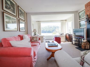 A living room with a sofa, coffee table, and television at Kiln Cottage in Golant near Tywardreath