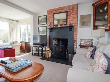 A living room with a fireplace and television at Kiln Cottage in Golant near Tywardreath