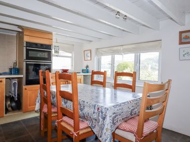 A kitchen with dining table and chairs at Kiln Cottage in Golant near Tywardreath
