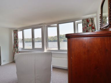 A living room with windows overlooking a water view at Kiln Cottage in Golant near Tywardreath