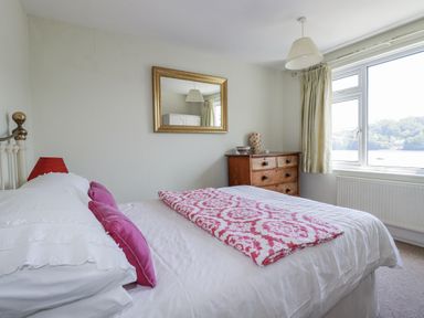 A bedroom with a bed and dresser at Kiln Cottage in Golant near Tywardreath