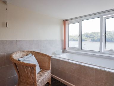 A bathroom with a bathtub and a chair at Kiln Cottage in Golant near Tywardreath