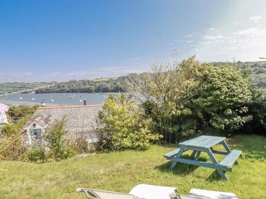 A garden with a picnic table and view of water at Kiln Cottage in Golant near Tywardreath