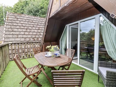 A balcony with a wooden table and chairs at Valley Lodge 20 Callington