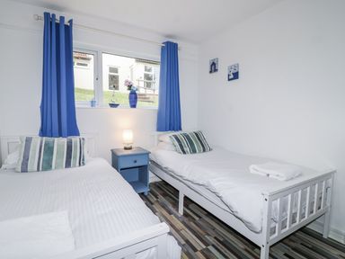 A bedroom with two beds and a bedside table at Manorcombe 21 Honicombe Holiday Village near Gunnislake