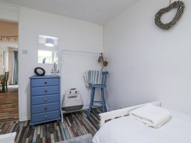A bedroom with a blue chest of drawers and a chair at Manorcombe 21 Honicombe Holiday Village near Gunnislake