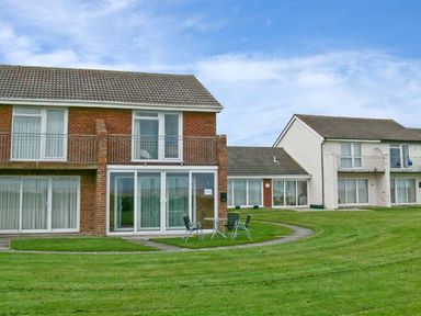 A view of two residential buildings with balconies and sliding glass doors on a grassy lawn at Seascape in Kessingland near Lowestoft