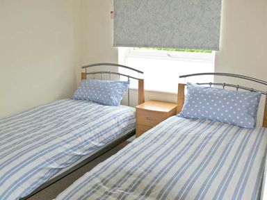 A bedroom with two single beds separated by a wooden bedside table at Seascape in Kessingland near Lowestoft