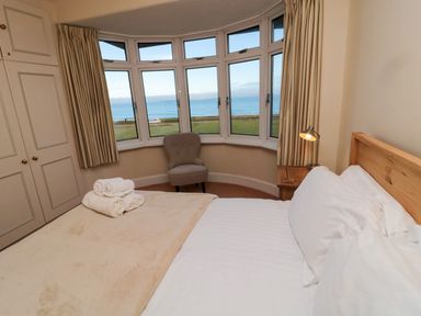 A bedroom with a bed and windows overlooking the sea at Glen Avon in Seahouses