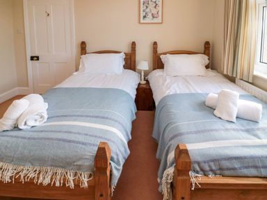 A bedroom with twin beds and a lamp at Glen Avon in Seahouses