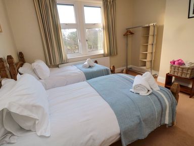 A bedroom with two beds and a clothes rack at Glen Avon in Seahouses