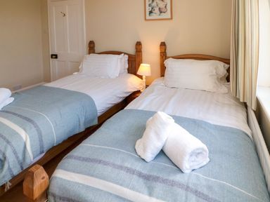 A bedroom with twin beds and bedside lamp at Glen Avon in Seahouses