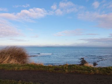 A view of the ocean and sky with grass and rocks at Glen Avon in Seahouses
