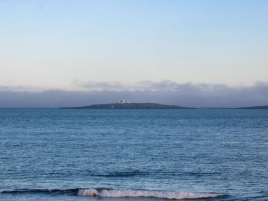 View of an island with a lighthouse from the ocean at Glen Avon in Seahouses