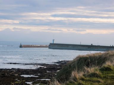 A view of a pier and lighthouse at Glen Avon in Seahouses