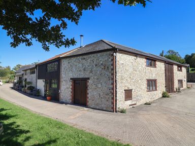 A stone building with windows and a driveway at The Granary Wyke Nr Axminster