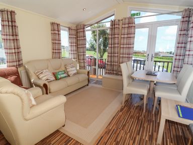 A living room with a sofa and dining area at Cody Cottage Lodge near Mullacott Park