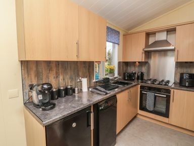 A kitchen with cabinets and appliances at Cody Cottage Lodge Mullacott Park near Ilfracombe