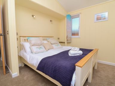 A bedroom with a bed and a window at Cody Cottage Lodge in Mullacott Park near Ilfracombe