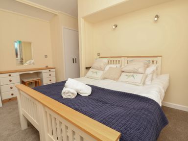A bedroom with a bed and dresser at Cody Cottage Lodge in Mullacott Park near Ilfracombe