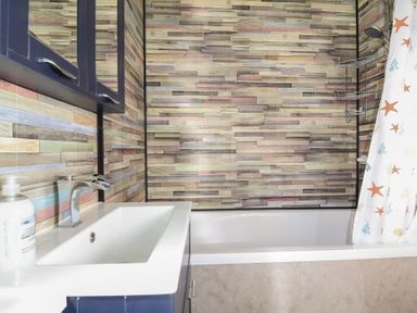 A bathroom with a sink, mirror, and bathtub at Cody Cottage Lodge, Mullacott Park near Ilfracombe
