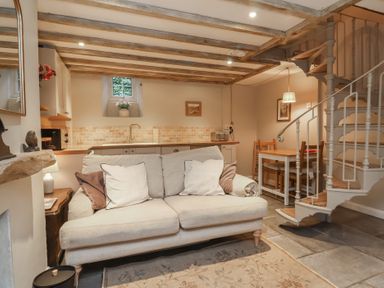 A living room with a sofa and kitchenette at Woodedge in Porlock