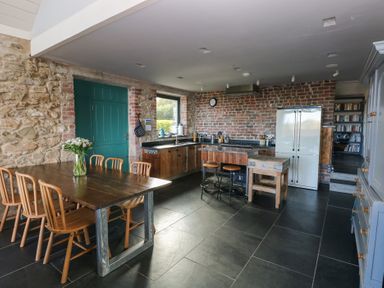 A kitchen with a dining table and refrigerator at The Barn in Newport