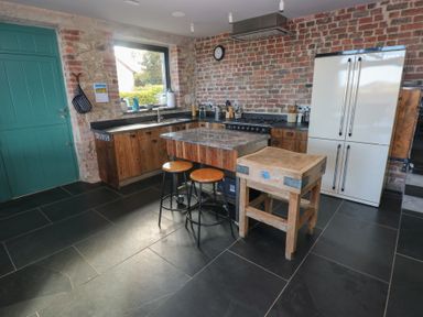 A kitchen with wooden counter and stools at The Barn in Newport