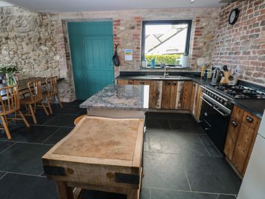 A kitchen with wooden cabinets and a stone wall at The Barn in Newport