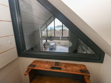 A loft area with a wooden bench and a view of the outdoor dining space at The Barn in Newport