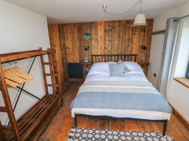A bedroom with a bed and wooden clothing rack at The Barn in Newport