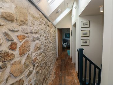 A hallway with a stone wall and wooden floor at The Barn in Newport