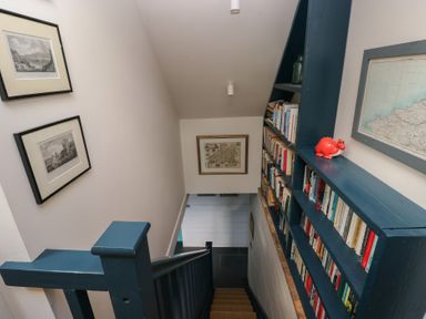 A staircase with a bookshelf and pictures at The Barn in Newport