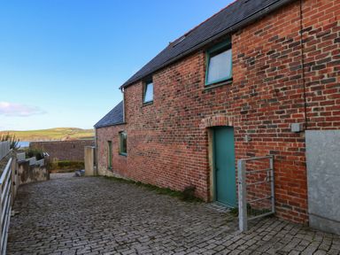 An exterior view of a brick building with paved path at The Barn in Newport