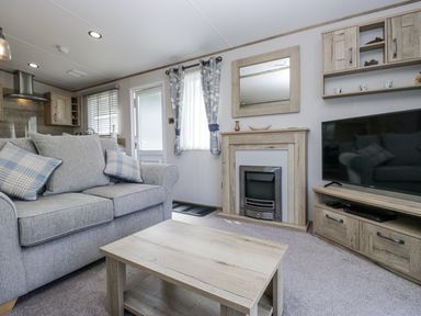 A living room with a sofa and television at Grasmoor View Lodge