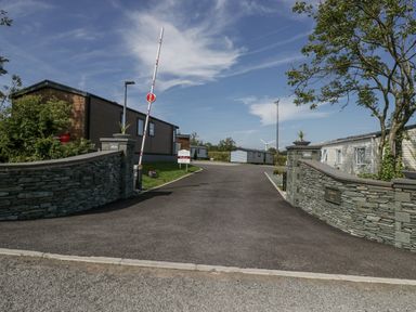 A stone wall with a gate and mobile homes at Grasmoor View Lodge