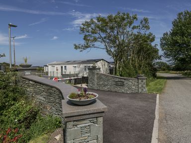 An outdoor entrance with a stone wall and caravan at Grasmoor View Lodge