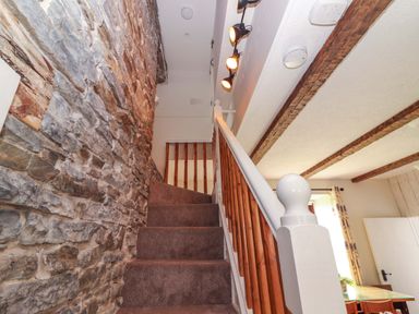A staircase with a stone wall and wooden railing at The Farmhouse in Tralee, County Kerry