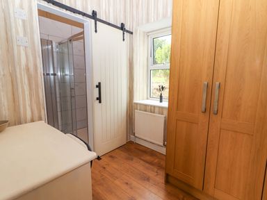A bathroom with a shower and a wardrobe at The Farmhouse in Tralee, County Kerry